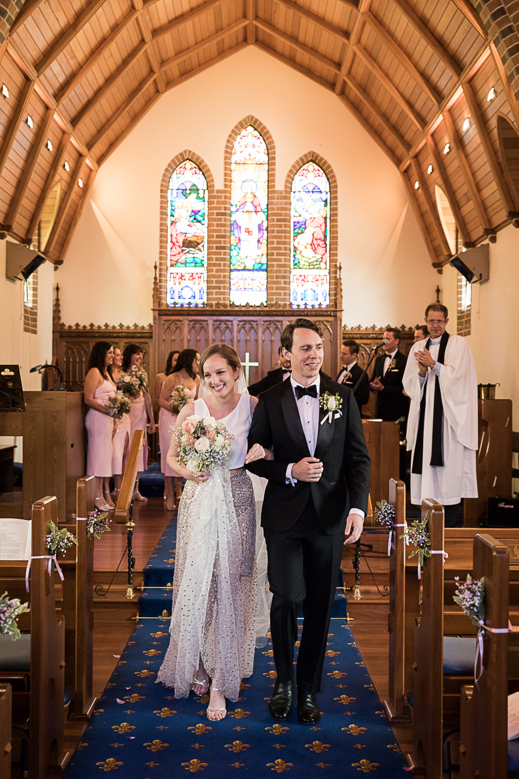 bride and groom walking out of church elated